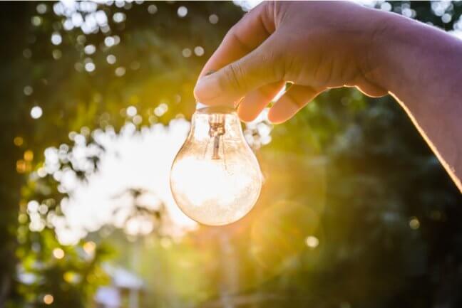 a hand holding an energised lightbulb outside